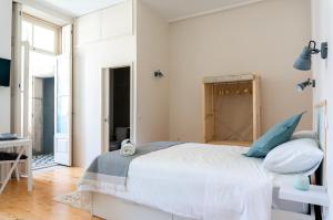 a white bedroom with a large bed with blue pillows at Jardim de São Lázaro - Porto Apartments in Porto
