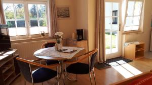 een eetkamer met een tafel, stoelen en ramen bij Ferienwohnung Frenzel in Kurort Gohrisch