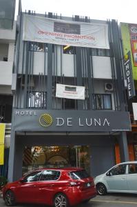 a red car parked in front of a hotel at De Luna Hotel Sri Petaling in Kuala Lumpur