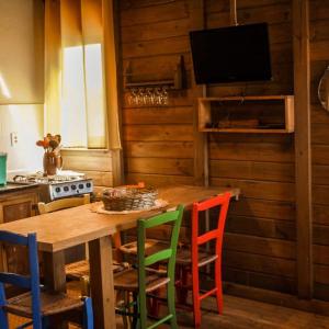 a kitchen with a wooden table with colorful chairs at Cabanas Mahalo in Imbituba