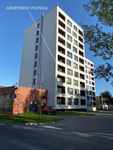ein hohes weißes Gebäude an der Straßenseite in der Unterkunft Apartment Poprad in Poprad