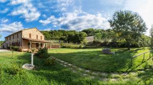an old brick building in a field with a grass yard at Agriturismo Bioli in Querceto