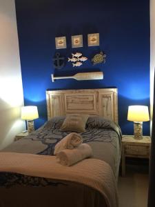a bedroom with a bed with blue walls and two lamps at Praia do Forte Apartamento Fantástico in Praia do Forte