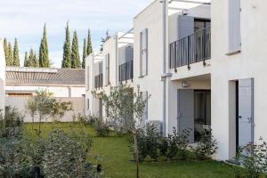 a row of white buildings with trees in the background at Les Cyclistes in Malaucène