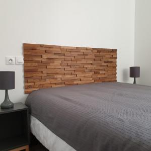 a bedroom with a large bed with a wooden headboard at La maison de toujours in La Garenne-Colombes