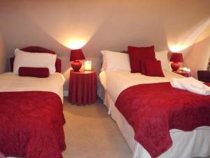 una camera con due letti rossi e bianchi di Hazel Bank Bed& Breakfast a Moffat