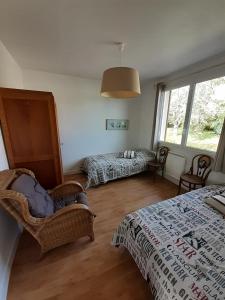 a bedroom with two beds and a chair and a window at Gites Nature & Espace - Le puits des souhaits in Villedieu-les-Poëles