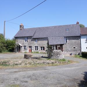 an old stone house with a black roof at Gites Nature & Espace - Le puits des souhaits in Villedieu-les-Poëles