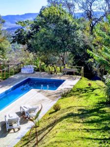 - une piscine dans un jardin avec 2 chaises et une table dans l'établissement Feliccità Pousada, à Extrema