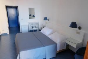 a bedroom with a large white bed with two lamps at Hotel Baia Di Puolo in Massa Lubrense