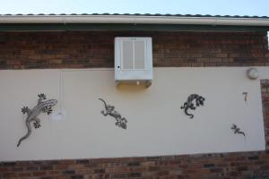 a wall with threeizards on it with a air conditioner at Woodlands Stop Over and Lodge in Francistown