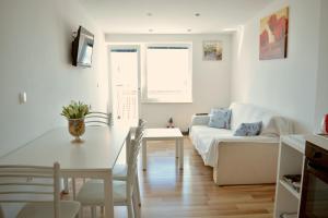 a white living room with a table and a couch at Apart-pansion Promajna in Promajna