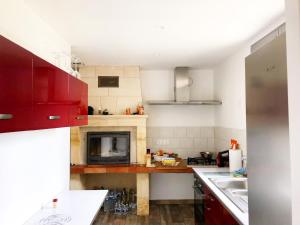 a kitchen with red cabinets and a stove top oven at Au lit de Vin in Saint-Sulpice-de-Faleyrens