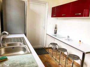a kitchen with a sink and two bar stools at Au lit de Vin in Saint-Sulpice-de-Faleyrens
