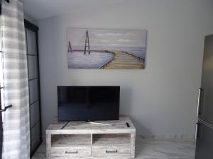 TV en un soporte de madera en la sala de estar en Appartamento Indipendente in Villa - Golf Del Sur, en San Miguel de Abona
