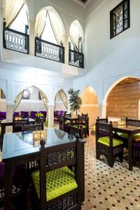 a restaurant with tables and chairs and windows at RIAD LA GAZELLE DU SUD in Marrakech