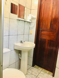 a bathroom with a sink and a toilet and a door at Pousada Ilha do Encanto in Ilha de Boipeba