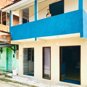 a woman sitting on the balcony of a house at Pousada Ilha do Encanto in Ilha de Boipeba