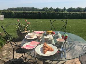 una mesa de cristal con cruasanes y teteras. en Thatched Cottage en Hungerford