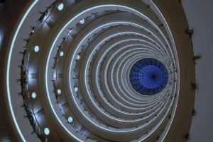 a spiral staircase in a building with a blue ceiling at Mövenpick Hotel Qassim in Buraydah