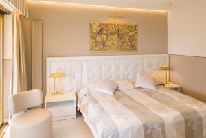 una camera con un grande letto bianco e una sedia di Hotel Ascona ad Ascona