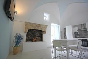 eine weiße Küche mit einem Tisch und einem Kamin in der Unterkunft Salentuosi - Salento Mille e una Notte in Racale