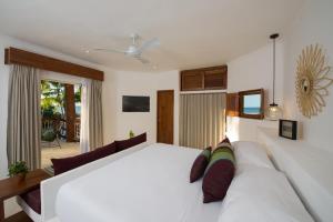 a bedroom with a large white bed with a couch at Villas HM Palapas del Mar in Holbox Island