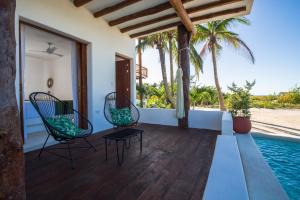 a patio with two chairs and a swimming pool at Villas HM Palapas del Mar in Holbox Island