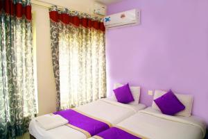 a bedroom with two beds with purple and white pillows at V bee Plaza in Trivandrum