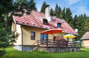 ein Haus mit rotem Dach und einer Terrasse mit Sonnenschirmen in der Unterkunft Chata Kadlečka in Lipno nad Vltavou