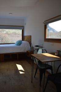 Schlafzimmer mit einem Bett, einem Tisch und einem Fenster in der Unterkunft Cerro Electrico - Off The Grid Tiny Houses in El Chalten