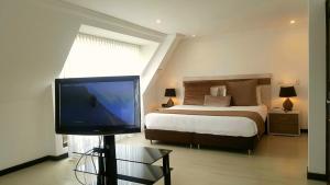 Un dormitorio con una cama y un televisor de pantalla plana. en Suites 109 GH Usaquén, en Bogotá