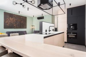 a kitchen with a large white counter top and black cabinets at City of the Kings-Bijou Apartment in Kraków