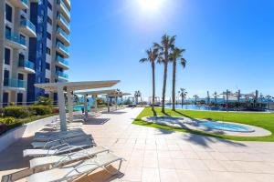 ein Resort mit Liegestühlen, einem Pool und Palmen in der Unterkunft CH Oasis Sea Senses Punta Prima in Torrevieja