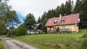 a house with a red roof on a hill with a dirt road at Chata Hansenka in Lipno nad Vltavou
