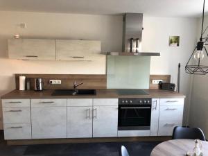 a kitchen with white cabinets and a sink and a stove at Ferienwohnung zum Heilbrünnchen in Emmelshausen