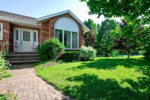 a brick house with a porch and a lawn at Lily's garden in Charlottetown