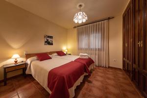 a bedroom with a large bed and a chandelier at Casa El Sastre III in Beceite