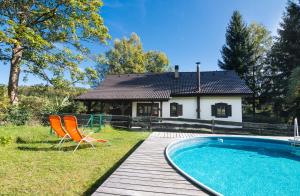 ein Haus mit einem Pool und zwei Stühlen auf einer Terrasse in der Unterkunft Vacation house KURTOVEC in Benešov nad Černou