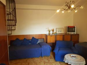 sala de estar con sofá azul y TV en Casa tranquilla e luminosa con terrazzo a due passi dal mare, en Brolo