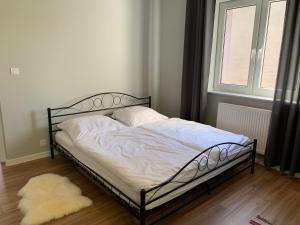 a bed in a room with a window and a rug at Grey apartment 50 m2 in Tarnowskie Góry