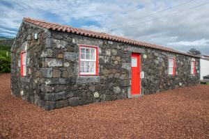 a stone building with a red door and windows at Casa Medronho in São Mateus