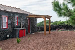a stone house with a red door and a pavilion at Casa Medronho in São Mateus +6 photos