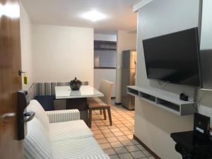 a living room with a table and a flat screen tv at PRAIA da COSTA ED PASSARGADA in Vila Velha