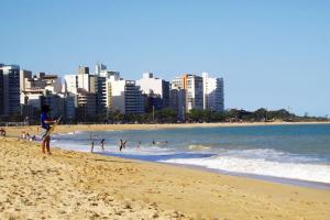 a beach with people in the water and a city at PRAIA da COSTA ED PASSARGADA in Vila Velha
