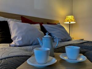 a table with two cups and a tea pot on a bed at Marszałka 28 in Jelenia Góra