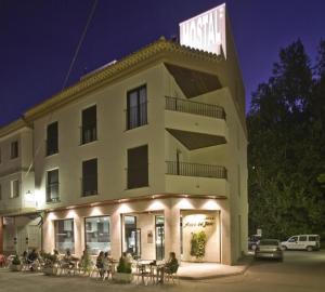 un gran edificio con gente sentada fuera de él en Hostal Alcalá Del Jucar, en Alcalá del Júcar