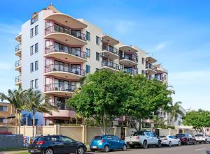 a tall apartment building with cars parked in front of it at Asiatic Suite at Nautilus Mooloolaba in Mooloolaba