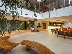 a lobby with wooden benches in a building at Mercure Salvador Rio Vermelho in Salvador