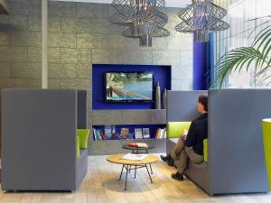a man sitting on a couch in a room with a tv at Aparthotel Adagio Muenchen City in Munich